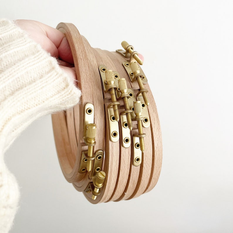 May include: A set of five wooden embroidery hoops with brass tightening knobs. The hoops are nested together and are ready to be used for crafting.