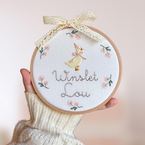 Embroidered plaque with baby’s name, nursery rhyme goose and a minimalist floral wreath | baby name announcement sign and nursery wall decor