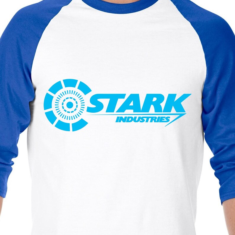 May include: A white and blue baseball t-shirt with a blue Stark Industries logo. The logo features a stylized circle with a smaller circle inside and the text "Stark Industries".