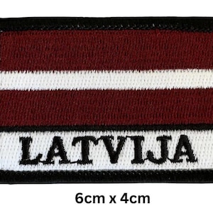 May include: Embroidered patch featuring the flag of Latvia. The rectangular patch has a maroon background with a white horizontal stripe and the word "LATVIJA" in black letters. The patch measures approximately 6cm x 4cm.