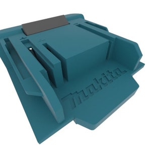 以下が含まれることがあります： 側面に「マキタ」という文字が刻印された、ターコイズブルーのプラスチック製のバッテリーホルダー。ホルダーの上部には黒いプラスチック製のインサートがあります。