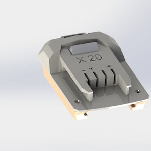 May include: A silver battery charger with the text "X 20" printed on it. The charger has a slot for a battery and a positive and negative terminal.