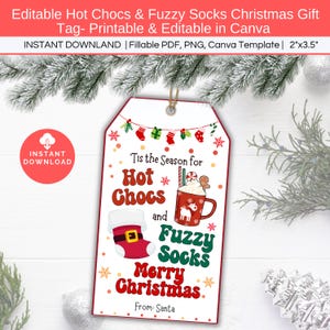 May include: A printable Christmas gift tag featuring a red mug of hot chocolate with marshmallows and a red fuzzy sock. The tag has the text "'Tis the Season for Hot Chocs and Fuzzy Socks Merry Christmas. From: Santa" in red and green text.