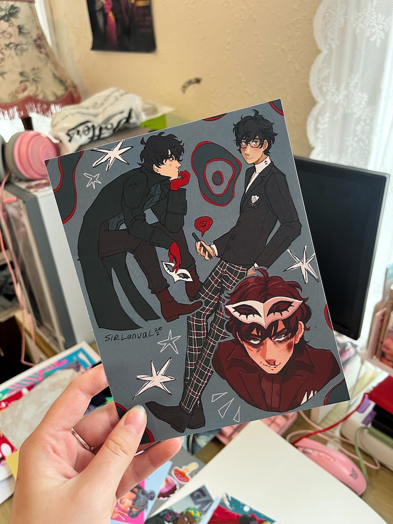 May include: A print featuring three characters from the Persona 5 video game. The characters are drawn in a cartoon style and are wearing their signature outfits. The print is set against a dark blue background with white stars and red circles.