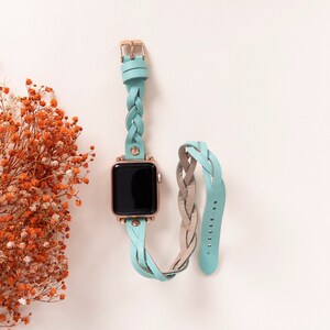 May include: A light blue braided leather watch strap with a rose gold buckle and a black watch face.