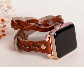 May include: A rose gold Apple Watch with a brown leather braided band. The band is wrapped around the watch twice.
