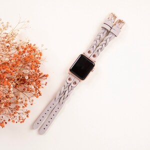 Peut inclure: Un bracelet de montre tress&eacute; gris clair avec des d&eacute;tails en or rose et un cadran noir. Le bracelet est compos&eacute; de deux sangles s&eacute;par&eacute;es qui sont tiss&eacute;es ensemble.