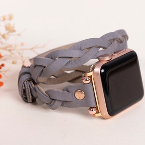 May include: A grey braided leather band for an Apple Watch with a rose gold finish.