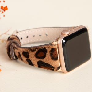 Op de afbeelding: Een Apple Watch in rosé goud met een luipaardprint band. De band is gemaakt van zacht nep bont.