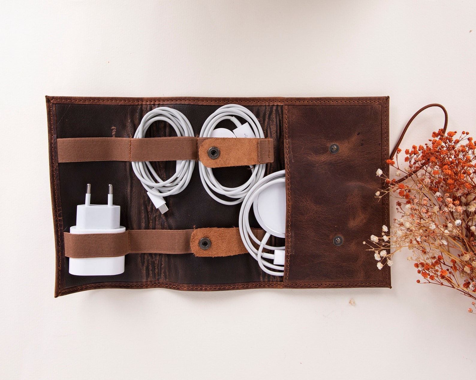 A leather cord manager with several power cords stored inside of it