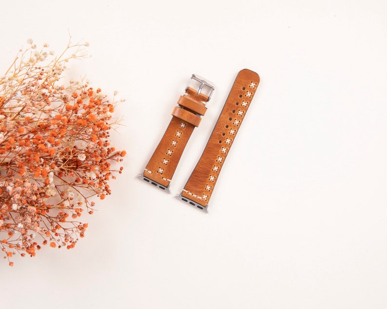 May include: Two brown leather watch bands with white stitching and silver hardware. The bands are on a white background.
