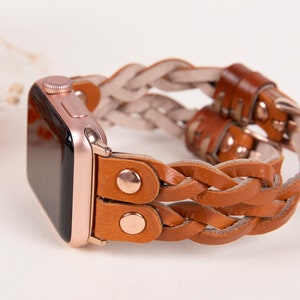 Peut inclure: Un bracelet de montre en cuir tress&eacute; de couleur marron et beige avec des d&eacute;tails en or rose. Le bracelet est con&ccedil;u pour une Apple Watch.