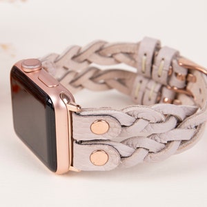 Peut inclure: Une Apple Watch en or rose avec un bracelet en cuir tress&eacute; gris clair. Le bracelet est compos&eacute; de deux rang&eacute;es de tresses et pr&eacute;sente des accents en or rose.