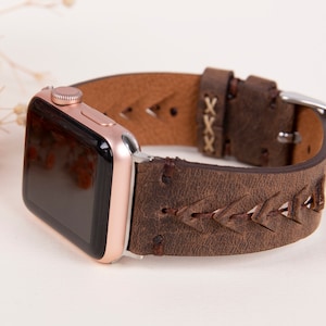 Puede incluir: Una correa de reloj Apple de cuero marr&oacute;n con un dise&ntilde;o trenzado y una hebilla plateada. La correa tiene un aspecto desgastado y est&aacute; hecha de cuero genuino.