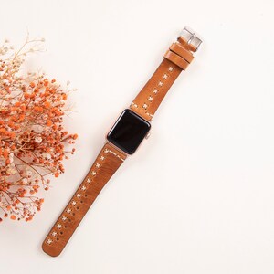 May include: A brown leather watch band with white stitching for an Apple Watch.