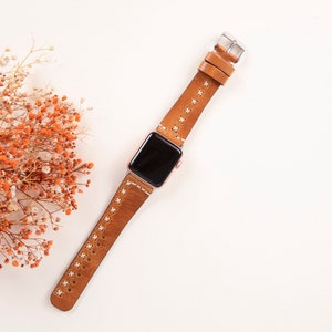 May include: A brown leather watch band with white stitching for an Apple Watch.
