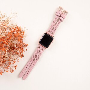 Peut inclure: Un bracelet de montre en cuir tress&eacute; rose avec des accents dor&eacute;s et un cadran noir.