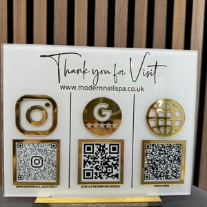 May include: White sign with gold accents featuring the text "Thank you for Visit" and the website address "www.modernnailspa.co.uk". The sign also includes gold icons for Instagram, Google, and a globe, along with QR codes for each platform.