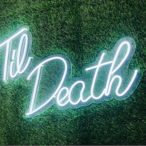 May include: White neon sign with the words "Til Death" on a green grassy background.
