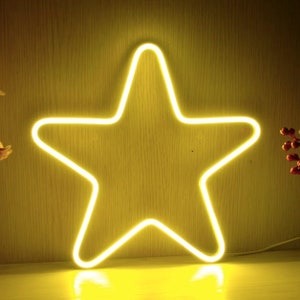 Peut inclure: Un luminaire en forme d'étoile en néon jaune sur un fond en bois.
