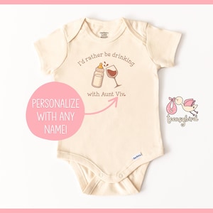 May include: Cream-colored baby onesie with the text "I'd rather be drinking with Aunt Viv." A baby bottle and wine glass are illustrated above the text. A pink circle with the words "Personalize with any name!" is on the left.