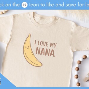 May include: Cream-colored toddler t-shirt with a smiling banana graphic and the text "I LOVE MY NANA." The shirt is made of soft material. A cute and fun design for kids.
