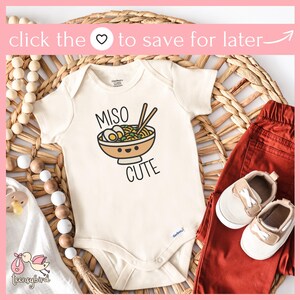 May include: A white baby onesie with a cartoon illustration of a bowl of miso ramen with chopsticks. The text "Miso Cute" is printed below the bowl.
