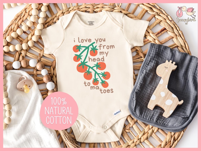 May include: A white baby onesie with short sleeves and a green tomato vine graphic. The onesie has the text 'i love you from my head to ma toes' printed on it. The onesie is 100% natural cotton.