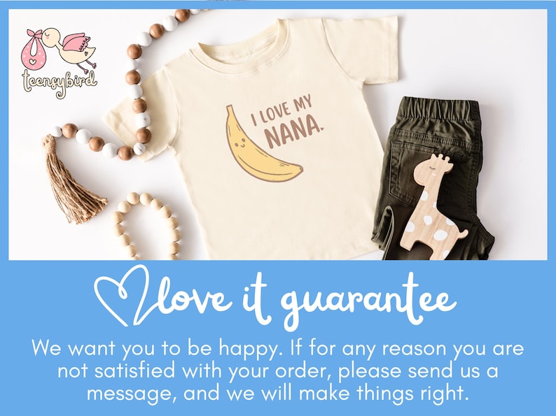 May include: Cream-colored baby tee with a banana graphic and the text "I LOVE MY NANA." The tee is paired with olive green pants and a wooden giraffe toy. A beaded garland and a tassel are also in the image.
