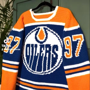 Peut inclure: Un pull en crochet bleu, orange et blanc avec le logo des Oilers et le numéro 97 sur le devant.