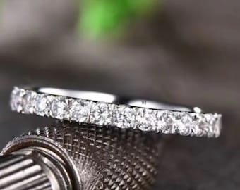 Puede incluir: Una fina banda de plata con una fila de pequeñas piedras redondas transparentes engastadas en pavé.