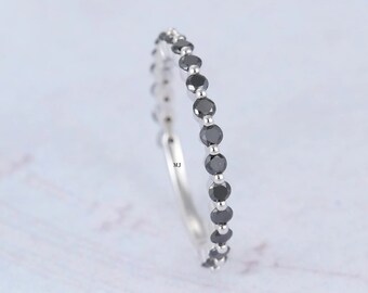 May include: A silver band ring with a row of small black gemstones.