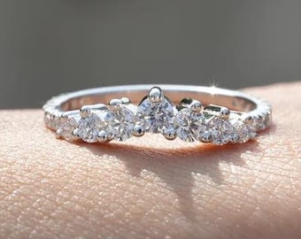 May include: A delicate silver band ring with a row of small, round, clear diamonds set in a curved, crown-like design.