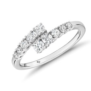 May include: A silver ring with a row of small diamonds on one side and a cluster of larger diamonds on the other side. The ring is marked "MJ".