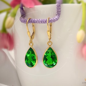 May include: A pair of gold drop earrings featuring pear-shaped green gemstones. The earrings have a simple design and are suitable for everyday wear.