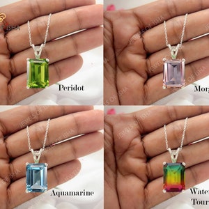 K&ouml;nnte beinhalten: Vier silberne Halsketten mit verschiedenen farbigen Edelsteinen. Die Halsketten haben einen quadratischen Anh&auml;nger mit einem gr&uuml;nen Peridot, einem rosa Morganit, einem blauen Aquamarin und einem Regenbogen-Wassermelonen-Turmalin.