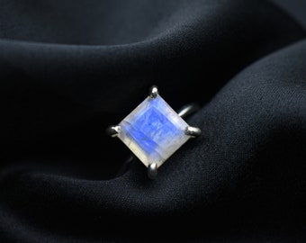 May include: A silver ring with a square-shaped moonstone. The moonstone is a light blue color with a shimmery effect.