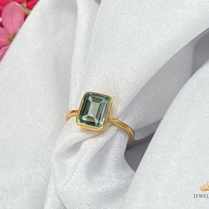 May include: A gold ring with a light blue emerald-cut gemstone.