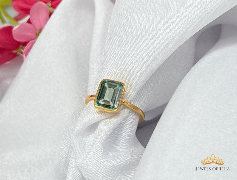 May include: A gold ring with a light blue emerald-cut gemstone.