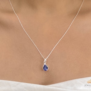 Può includere: Una collana a catena d'argento con un ciondolo a forma di lacrima con una pietra preziosa blu scuro.
