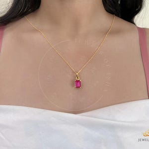 May include: A gold chain necklace with a pink rectangular gemstone pendant.