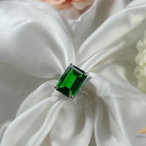 Puede incluir: Un anillo de plata con una gran piedra preciosa rectangular de color verde esmeralda.