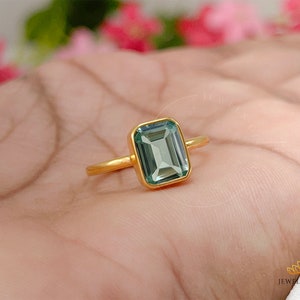 May include: A gold ring with a light green emerald-cut gemstone.