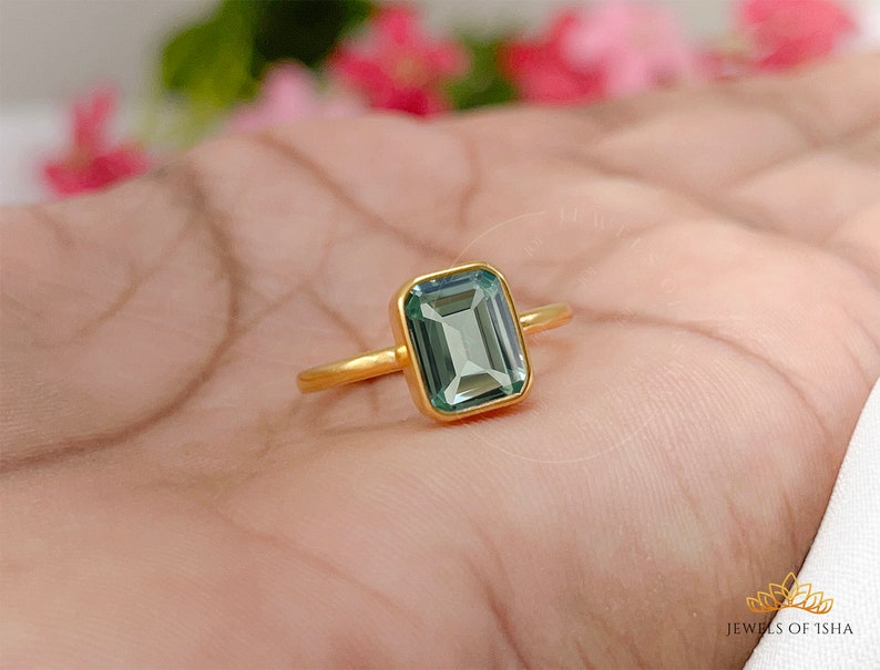 May include: A gold ring with a light green emerald-cut gemstone.