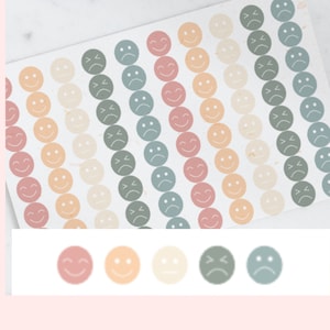 May include: A sheet of colourful smiley face stickers with different expressions. The stickers are arranged in rows and are in shades of pink, orange, beige, green, and blue.