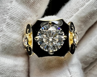 May include: A gold ring with a large, clear, round gemstone set in a black enamel bezel. The ring has a decorative design with smaller gemstones on the sides.