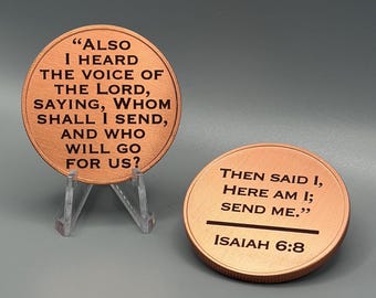 May include: Two circular copper-toned tokens featuring engraved black text. One token rests on a clear plastic stand, displaying the text: "ALSO I HEARD THE VOICE OF THE LORD, SAYING, WHOM SHALL I SEND, AND WHO WILL GO FOR US?" The other lies flat, reading: "THEN SAID I, HERE AM I; SEND ME." and "ISAIAH 6:8".