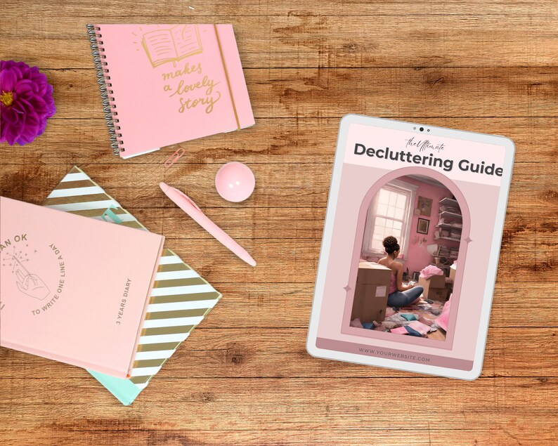 May include: A pink tablet computer displaying a decluttering guide with the text "Decluttering Guide" and "thel t" at the top. The guide features a photo of a woman sitting in a messy room, surrounded by boxes and clothes. The text "www.yourwebsite.com" is at the bottom of the guide.