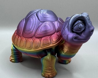 May include: A rainbow iridescent 3D printed turtle figurine with a detailed shell and a whimsical expression.