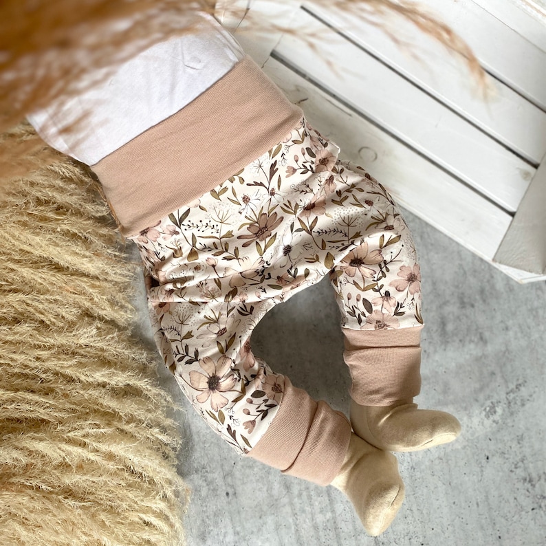 Pumphose für Babys und Kleinkinder. Babyhose für Mädchen mit Blumenmotiv. Dehnbares Bauchbund, wächst 1 - 2 Größen mit. Stoff ist schadstoffgeprüft. Farbe beige / rosé. Größen 56 - 104